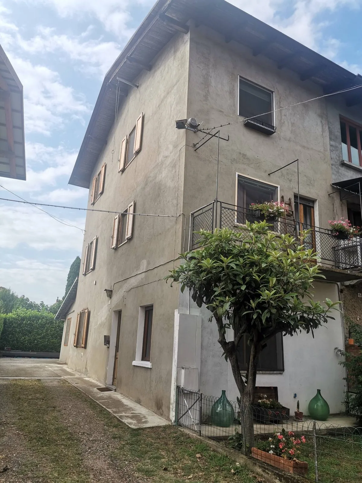 Casa Aura vista dal cortile, con il giardino e i vasi di fiori